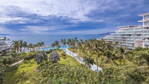 A resort with a pool, palm trees, and a view of the sea. - Peninsula Deluxe Resort, 4 BR, Great Ocean Views, Great amenities (Flamingos)