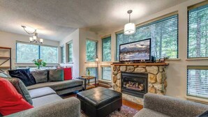 A living room with a stone fireplace, a television, and a sofa.