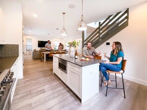 Una cocina moderna con una isla central, un área de comedor con sofá y una escalera.