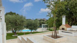 Un giardino pensile con piscina, alberi e una piccola costruzione in pietra.