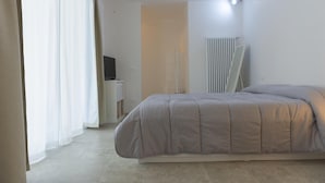 Una camera da letto con un letto, una scrivania, un termosifone e una finestra con tende.