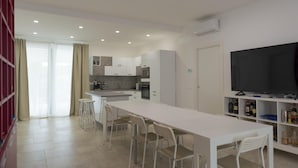 Una cucina moderna con mobili bianchi, un'isola grande e una TV a schermo piatto.