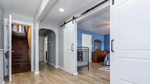 A hallway with a wooden staircase, a white door, and a baby gate. - Bluebonnet Surprise-Lakefront, Hot Tub, Boat Slip (Kingsland)