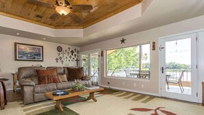 A living room with a sofa, coffee table, and a view through a glass door. - Bluebonnet Surprise-Lakefront, Hot Tub, Boat Slip (Kingsland)