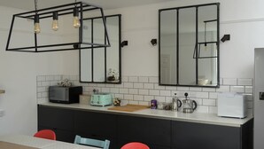A modern kitchen with a white countertop, black cabinets, a toaster, a kettle, and a refrigerator.