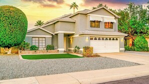 Une maison à deux étages avec un garage, une pelouse bien entretenue et une grande haie.