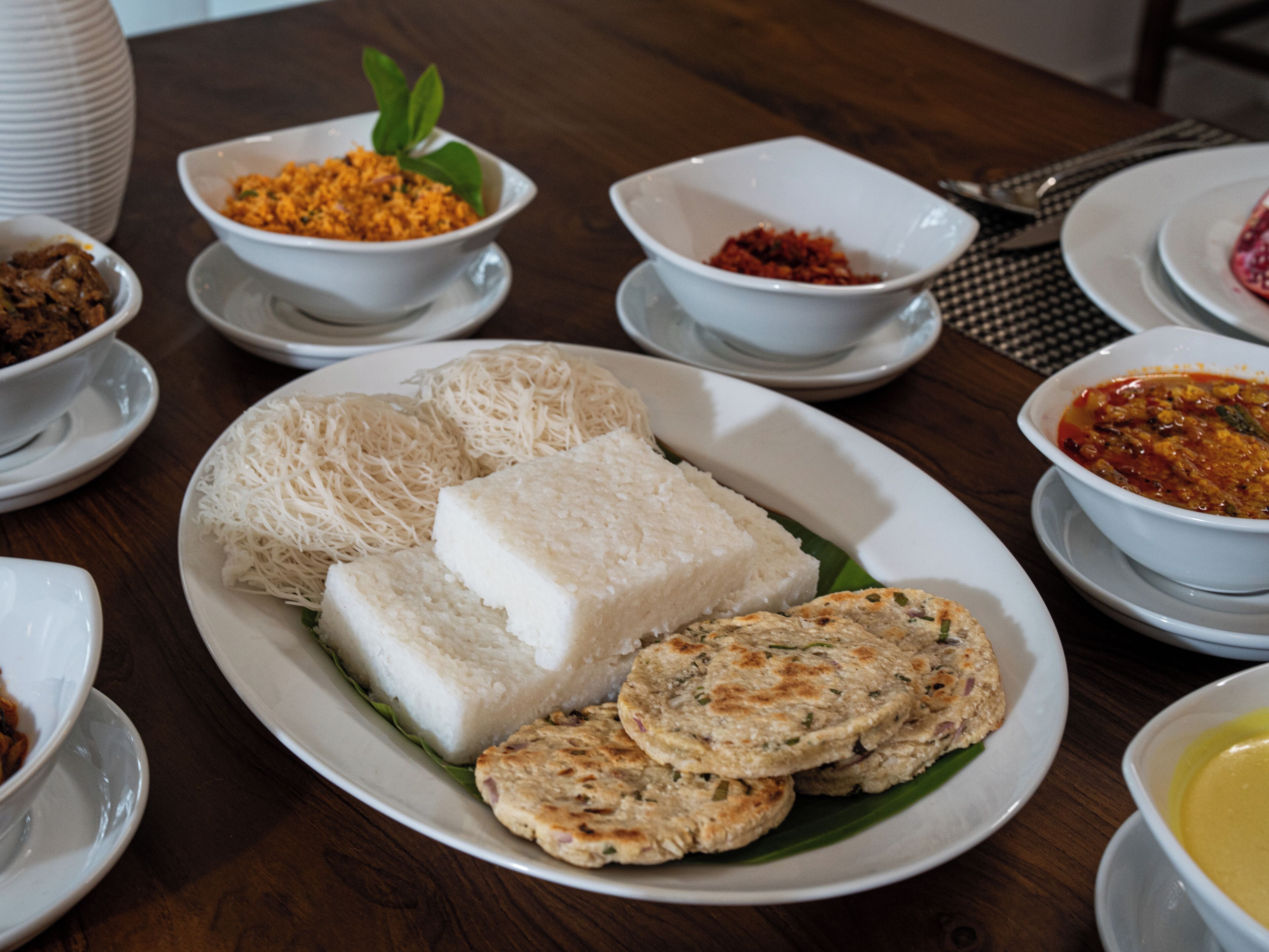 A table with various dishes including rice, noodles, and a bowl of soup.