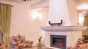 Ein Wohnzimmer mit floralen Sofas, einem Kamin und einer Blumenvase.