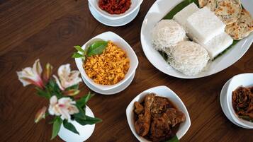 Uma mesa com diversos pratos, incluindo arroz, macarrão e carne, indicando um ambiente de refeição.