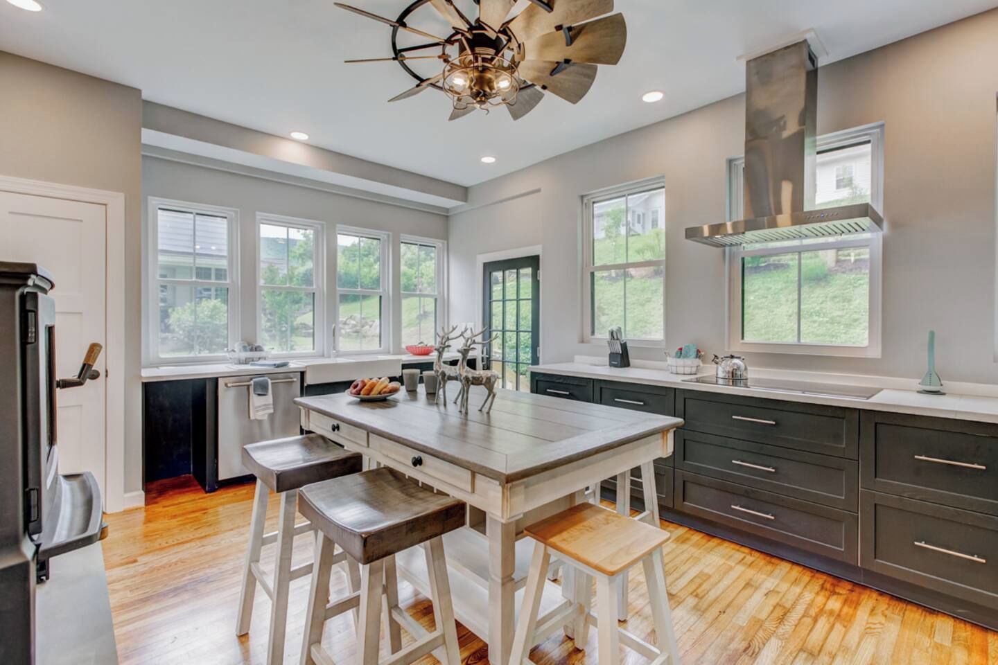 A modern kitchen with a central island, bar stools, and a large window.