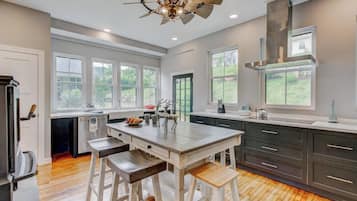 A modern kitchen with a central island, bar stools, and a large window.