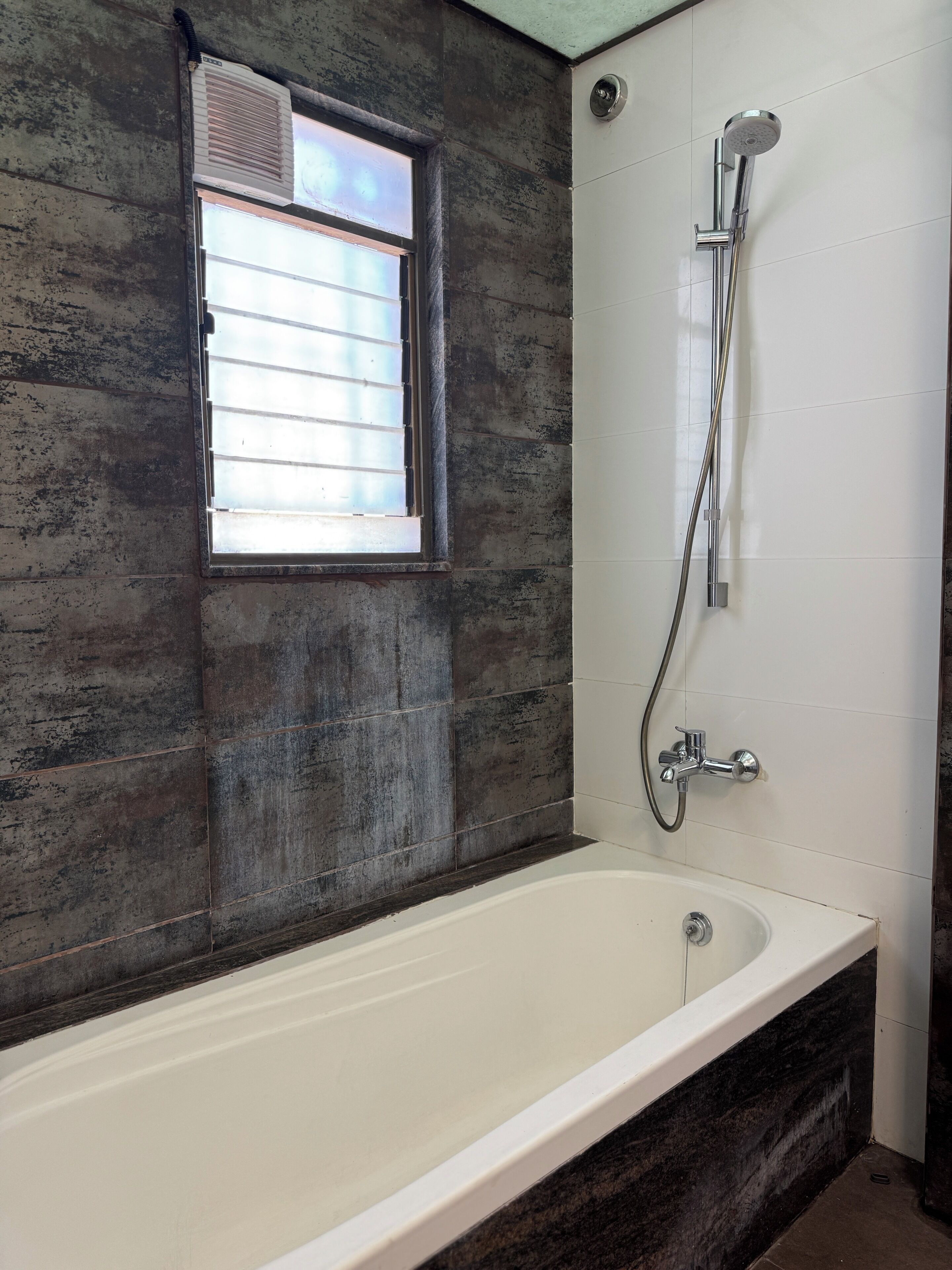 A bathroom with a bathtub, a shower, and a window with blinds.