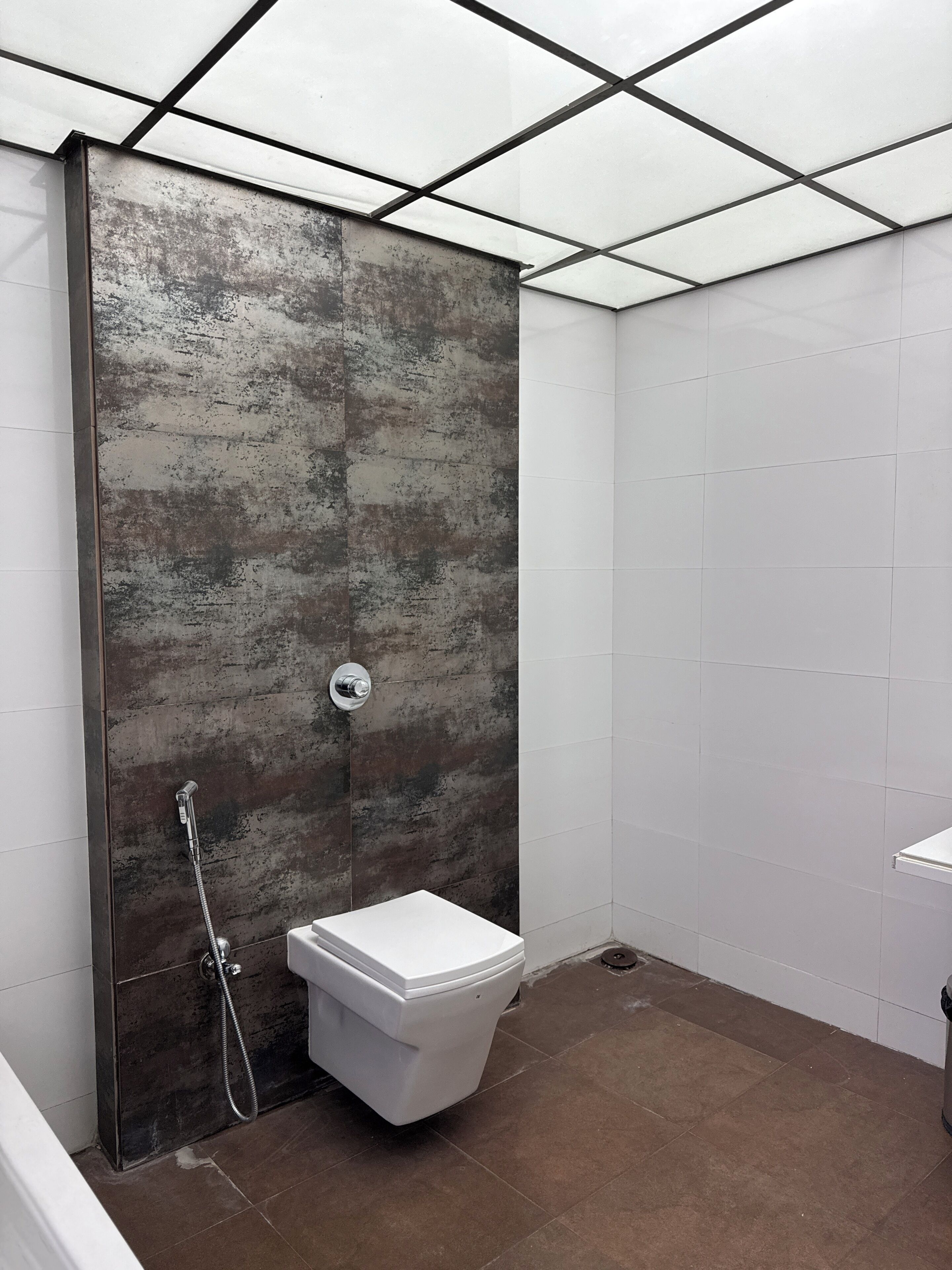 A bathroom with a shower, toilet, and a tiled floor.