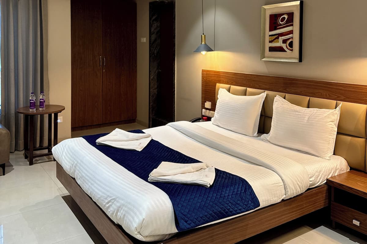 Una camera d'albergo con un letto, comodino, quadro appeso al muro, ventilatore a soffitto e condizionatore d'aria.