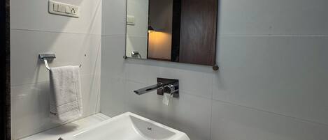 Un baño moderno con un lavamanos blanco, un espejo y un perchero para toallas.
