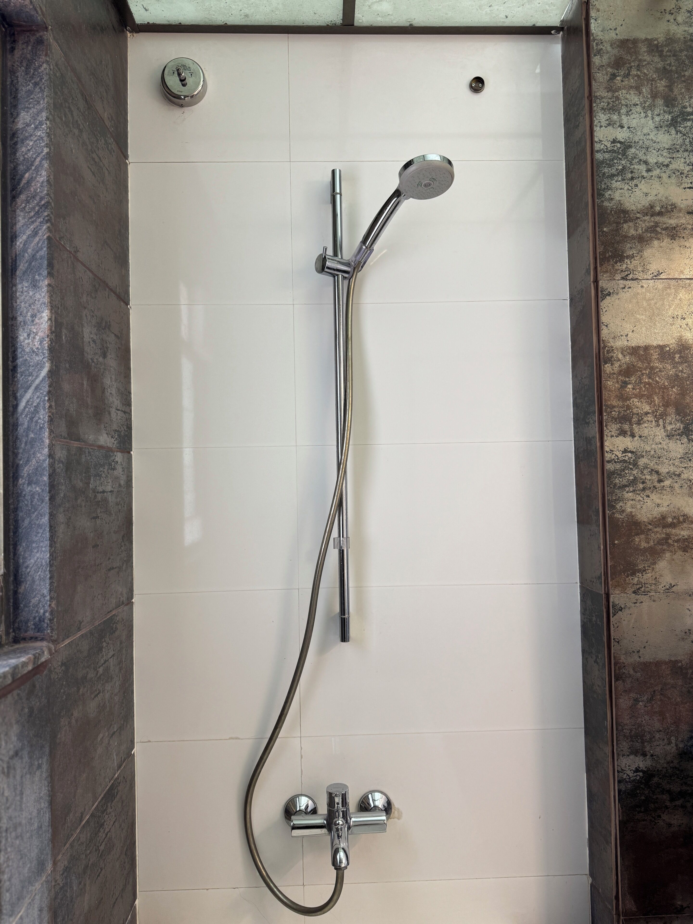 Ducha con cabezal de ducha manual, grifo empotrado en la pared y mando de control.