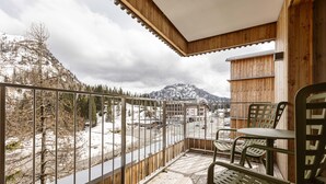 A wooden deck with metal railings, a table, and chairs. - Premium Lodge With Sauna (Hermagor-Pressegger See)