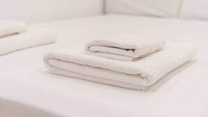 A neatly folded white towel stacked on a white surface, likely a bathroom counter or table.