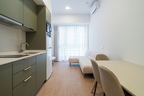 Cozinha moderna com pia, armários e janela com cortinas leves.