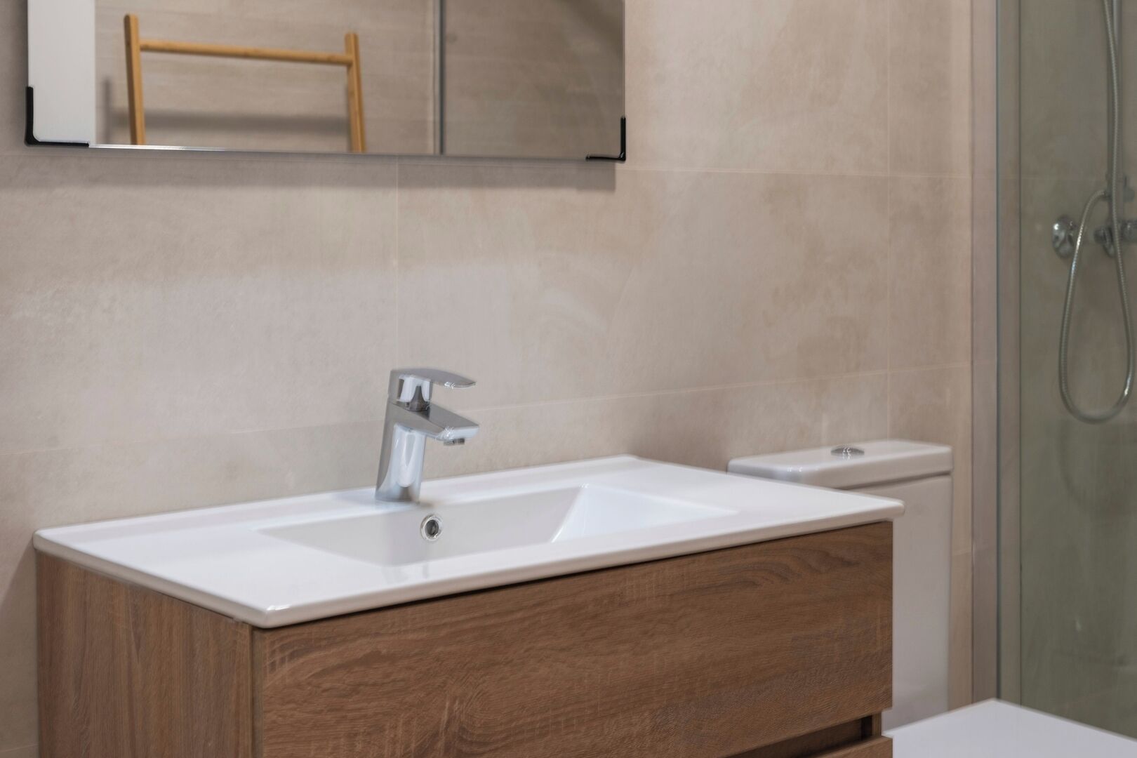 Une salle de bain avec un lavabo blanc, un meuble-lavabo en bois et une cabine de douche en verre.
