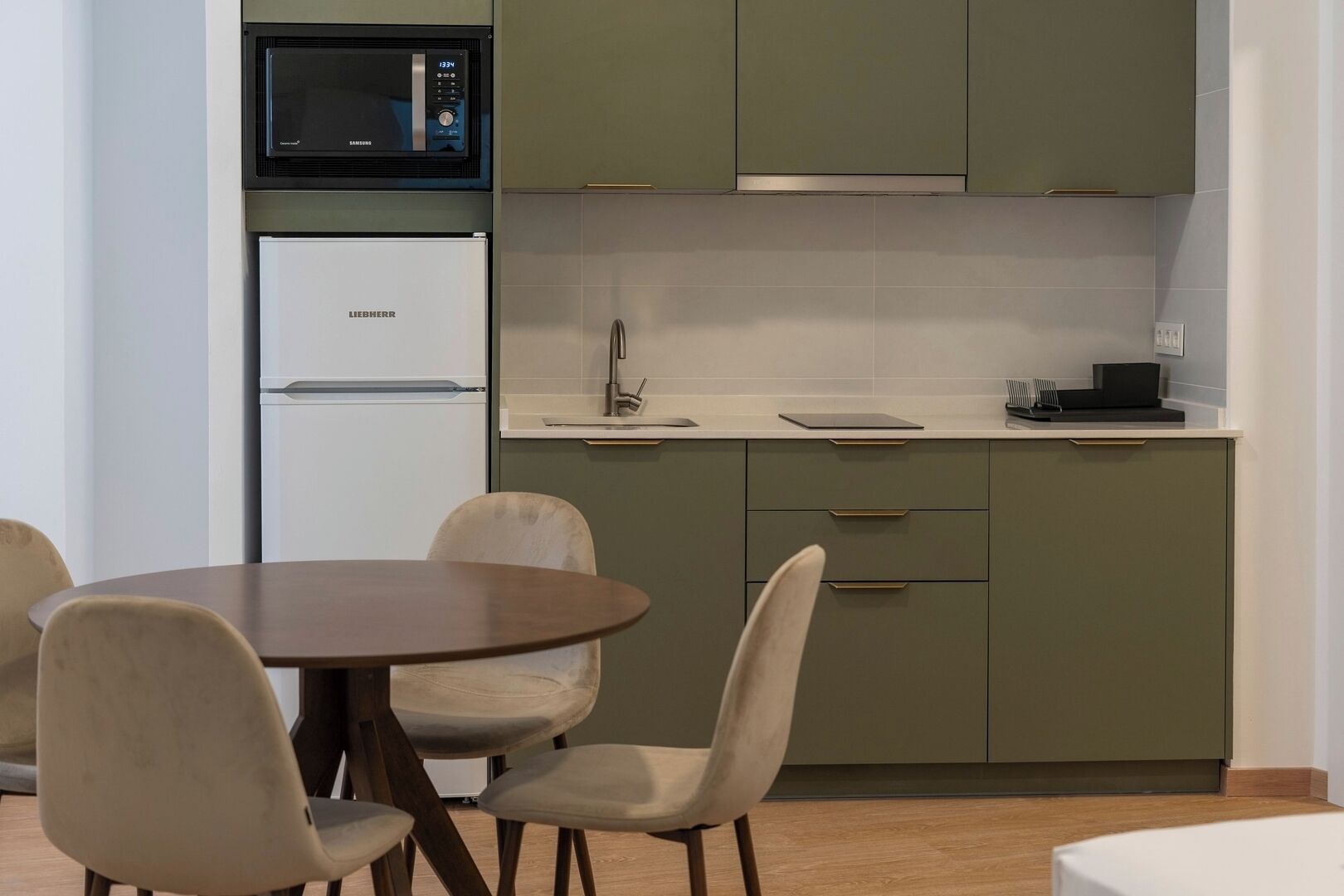 Une cuisine compacte équipée d’un four à micro-ondes, d’un réfrigérateur et d’un coin repas avec une table et des chaises.