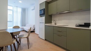 A compact kitchen with a microwave, sink, and green cabinets. There's a dining area with a table and chairs. - VLC HOST- Molinell 7 (Valencia)