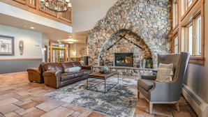 Eine geräumige Lobby mit Kamin aus Stein, Ledersofas und einer hohen Decke mit Holzgeländern.