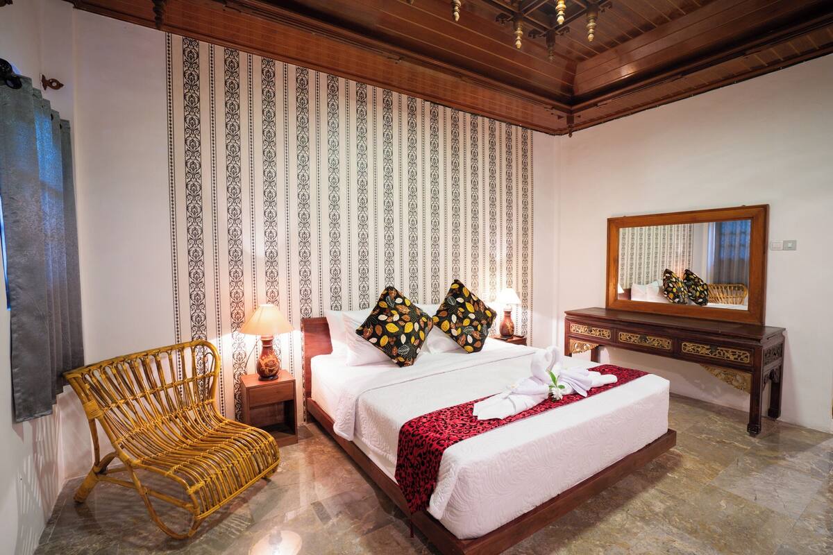 A neatly arranged bedroom with a bed, a chair, a nightstand, and a dresser.