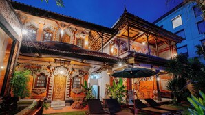 Un edificio tradicional con arquitectura ornamentada, piscina y mobiliario exterior.