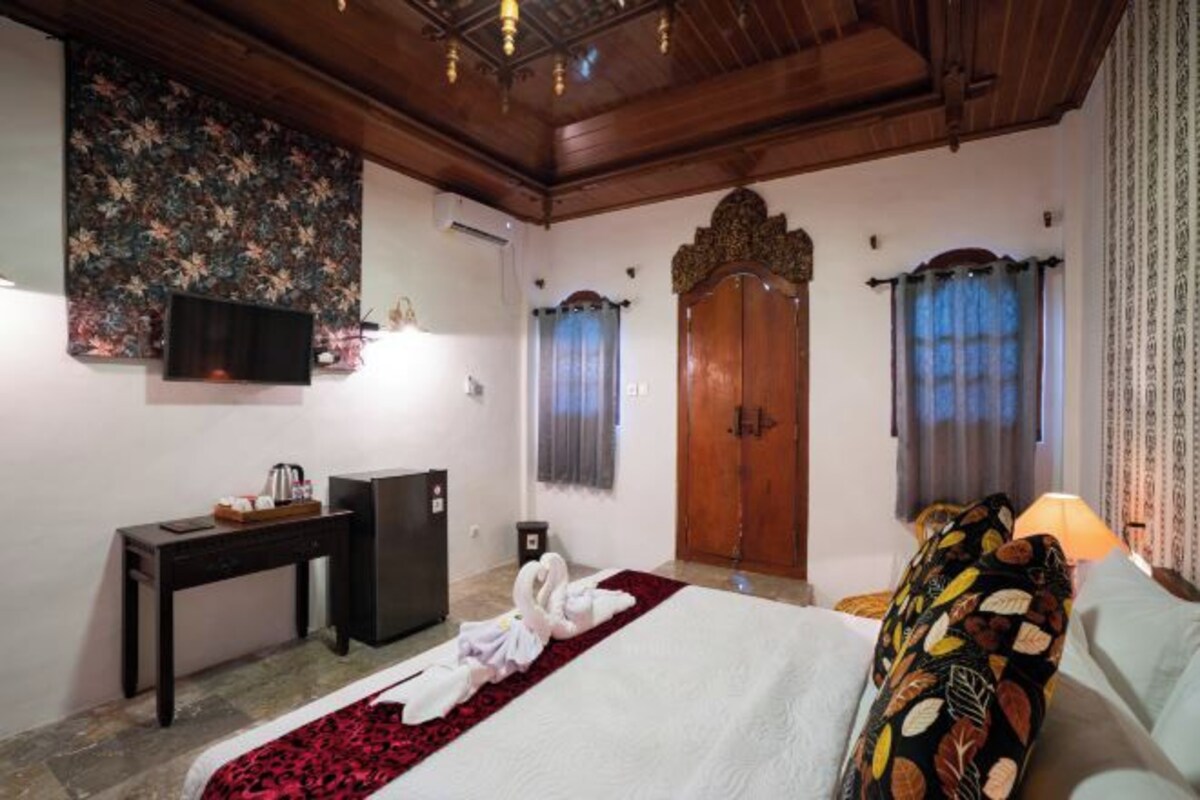 A hotel room with a bed, a desk, a television, and a wardrobe.