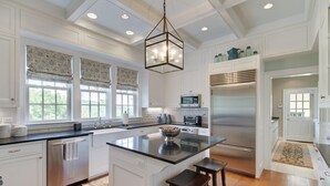 A spacious kitchen with white cabinetry, a stainless steel refrigerator, a microwave, and a large island with stools. - Luxury Home w/ Mtn Views, 1 Mile to the Homestead! (Hot Springs)