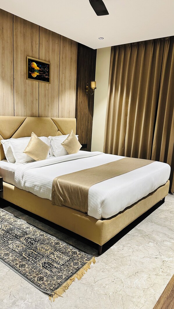 A large bed with a headboard, a wall-mounted light fixture, and a patterned rug. - HOTEL HRISHIKESH HIGH (Rishikesh)