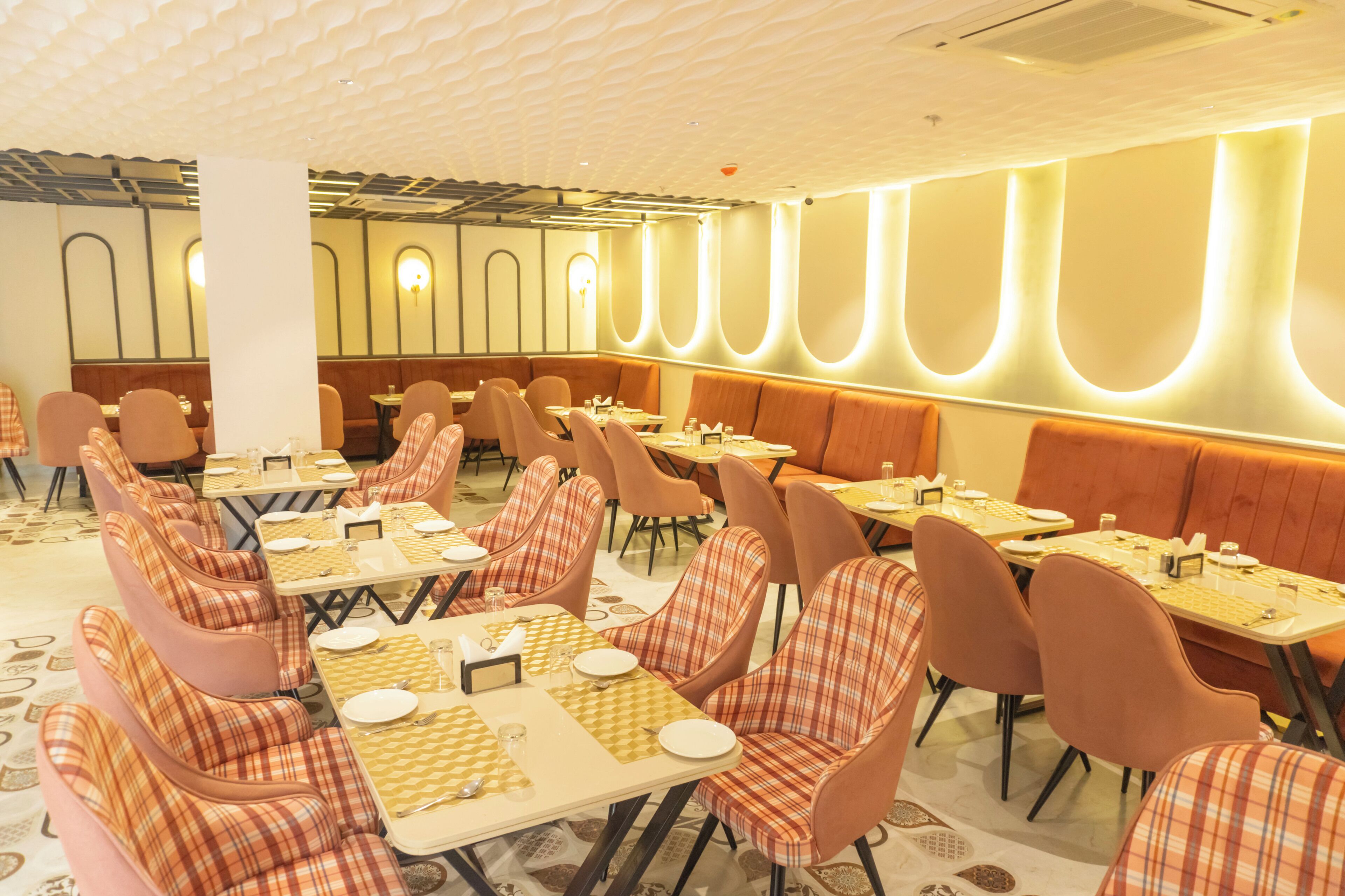 Un restaurante con sillas y mesas a cuadros, un suelo estampado y una pared con una lámpara.