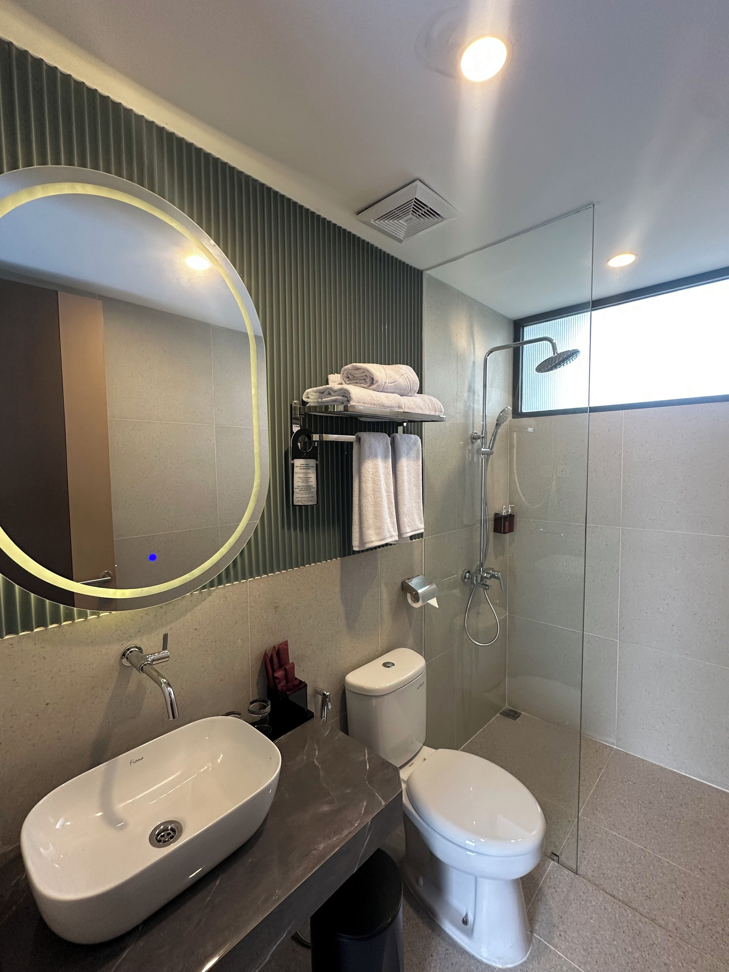 A modern bathroom with a vanity, two sinks, a toilet, and a shower.