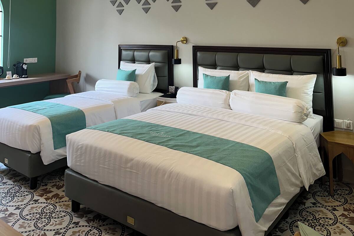 Une chambre d’hôtel avec deux lits, un bureau et un panneau décoratif au mur.