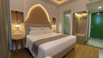 A modern hotel room with a large bed, bedside lamps, a wooden nightstand, and a green door.