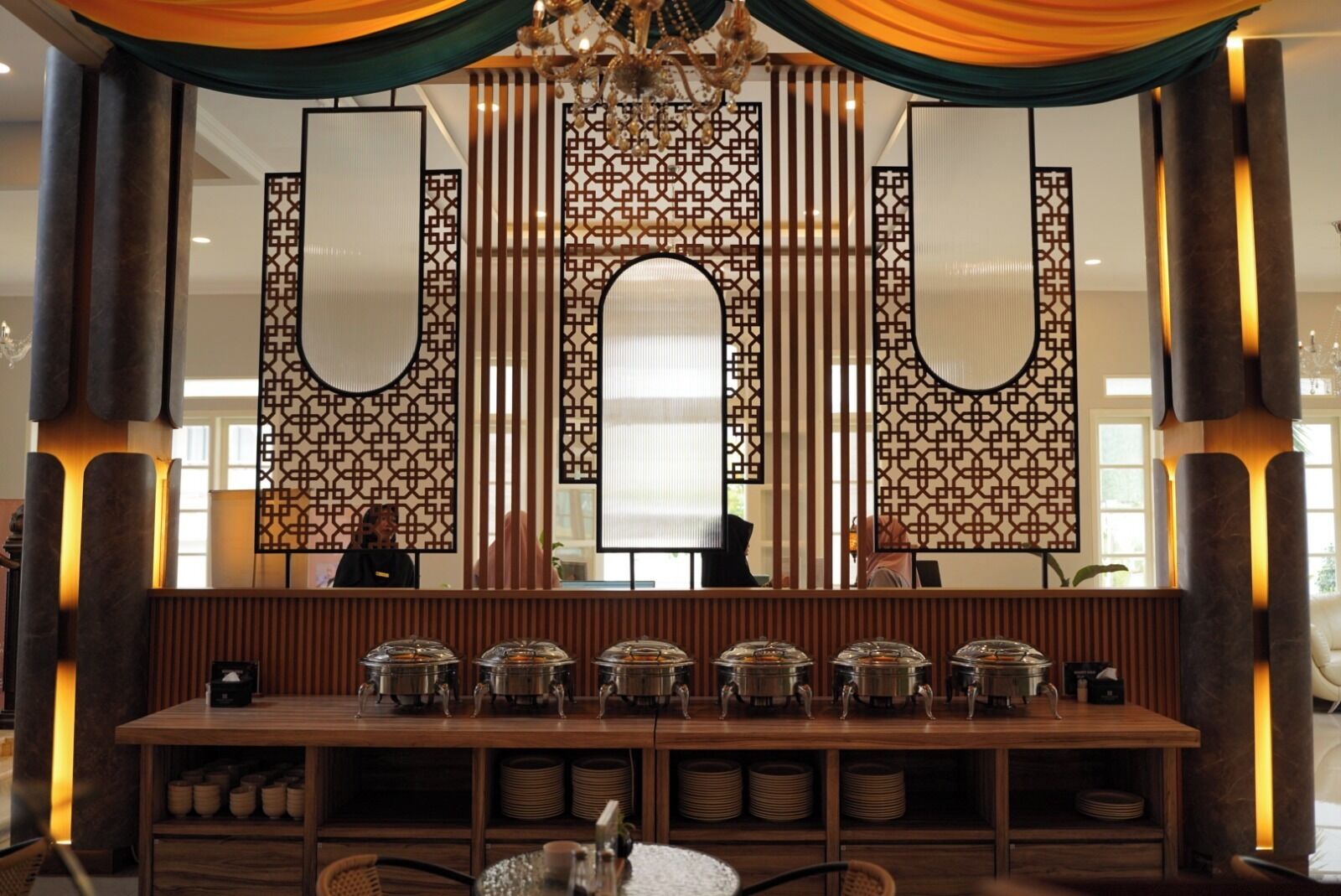 A reception area with a long wooden counter, multiple tea pots, and a decorative screen with vertical lines.