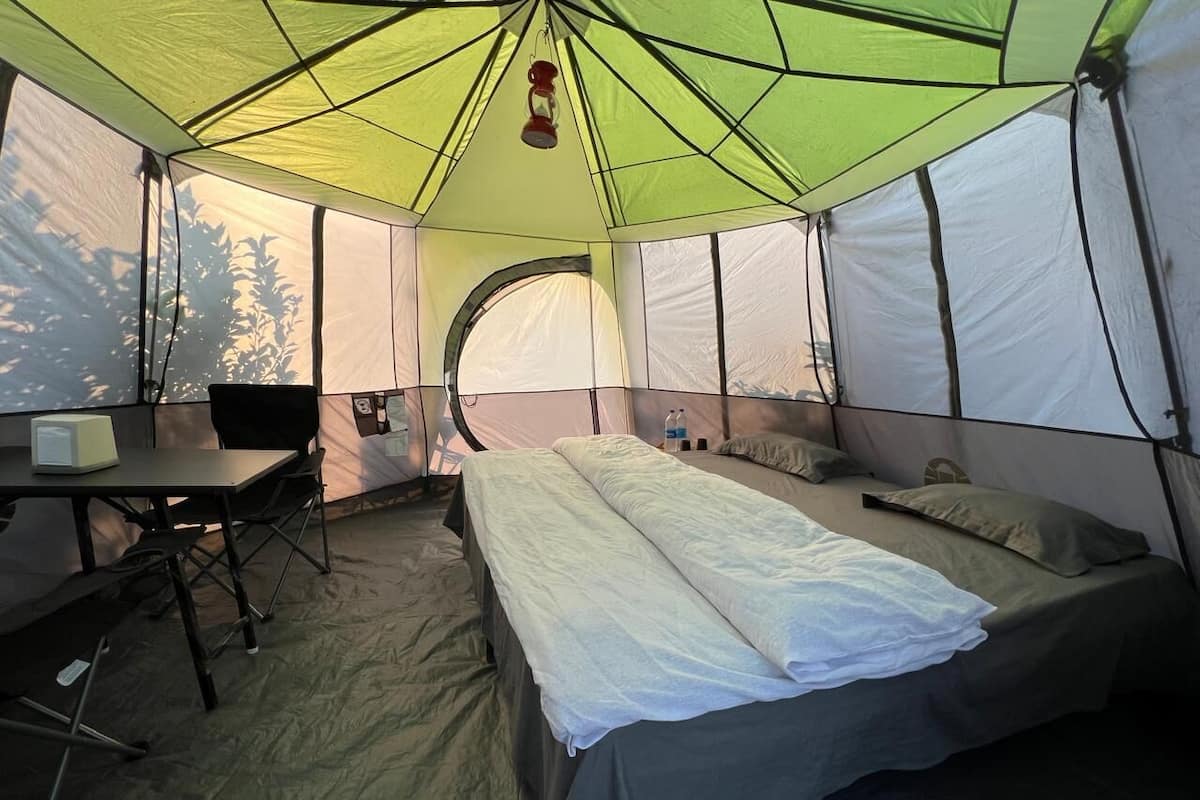 A tent with a bed, a table, and a chair.