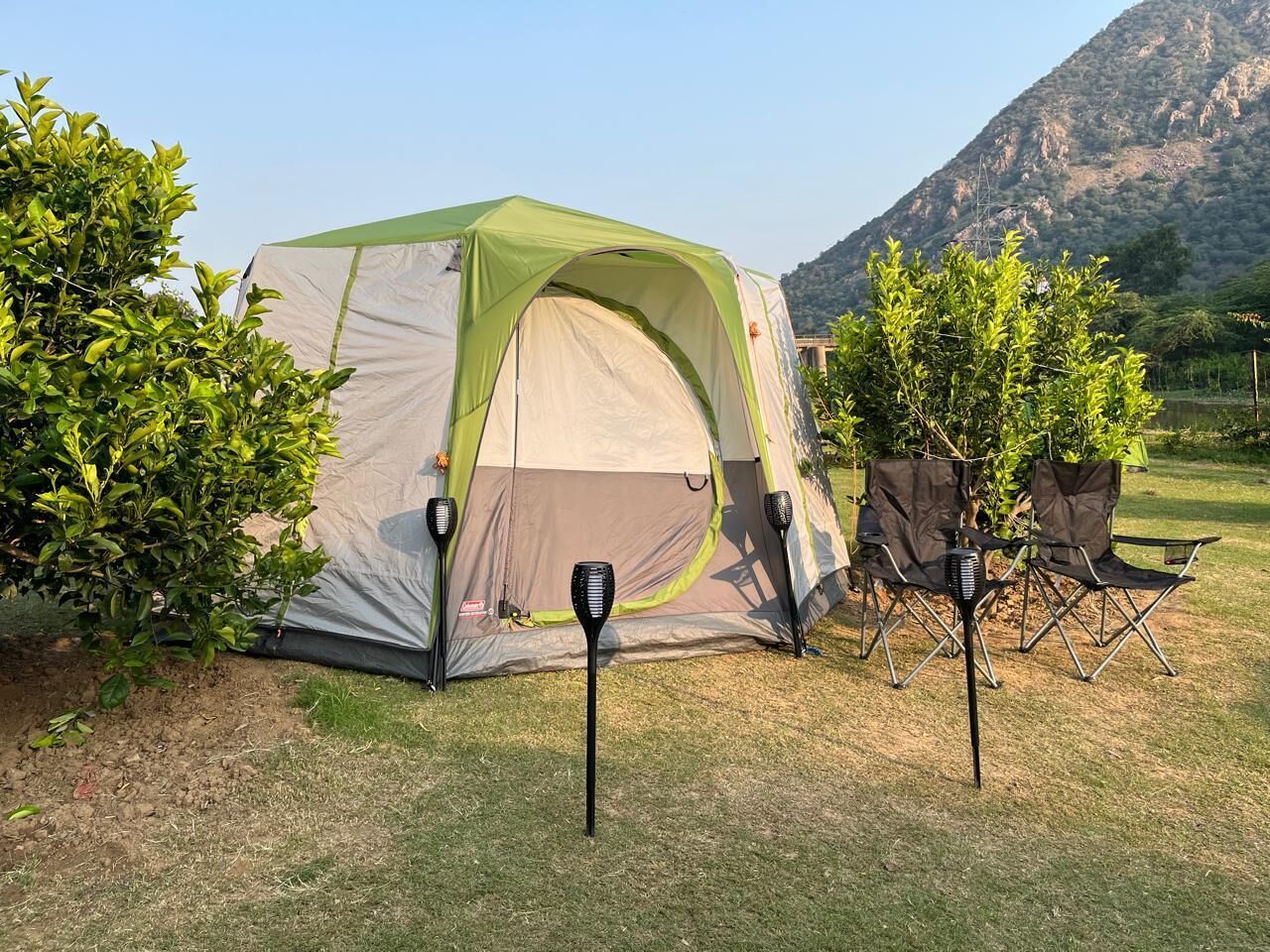 A camping setup with a tent, two chairs, and a portable speaker.
