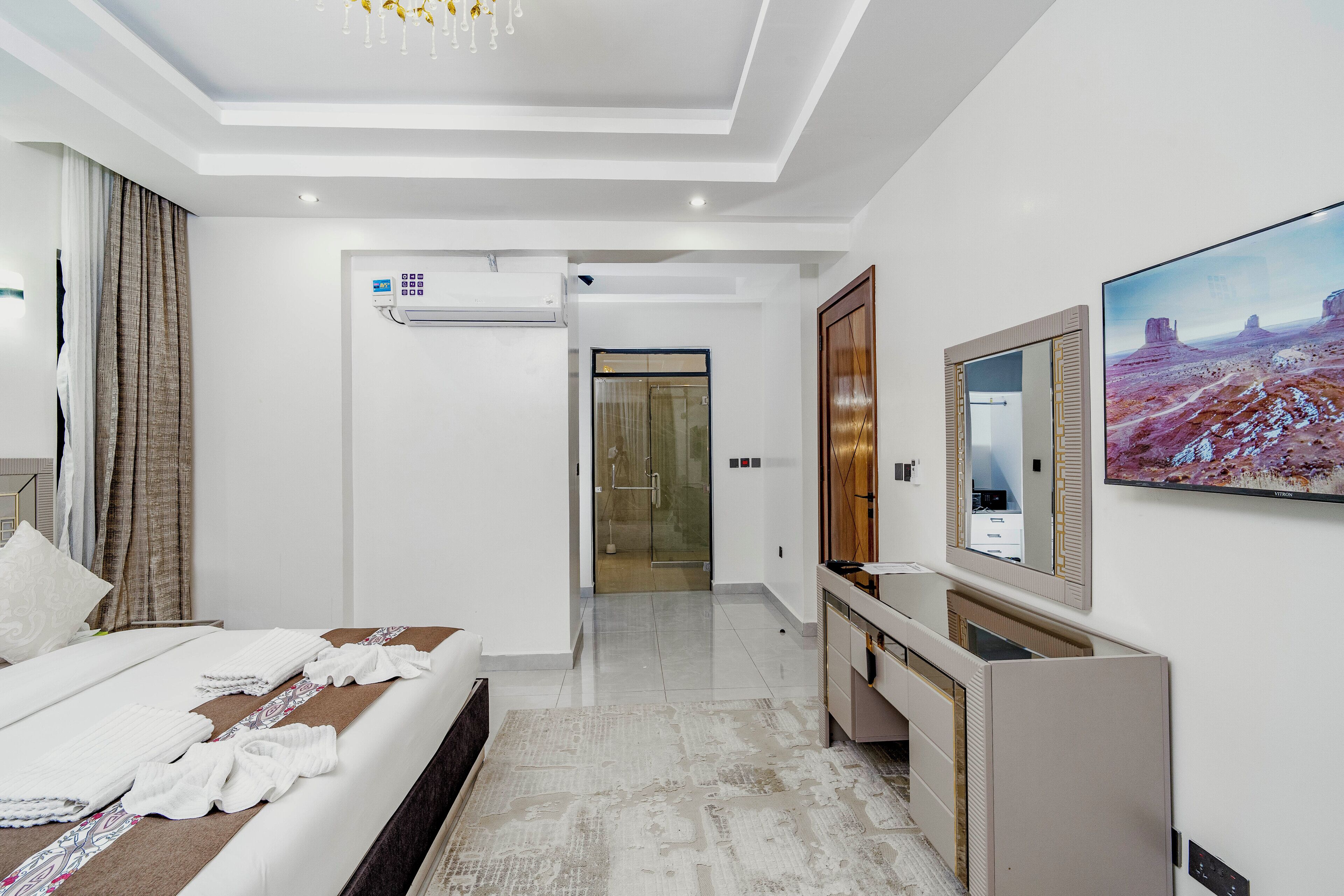 Een hotelkamer met een bed, bureau, spiegel en televisie.