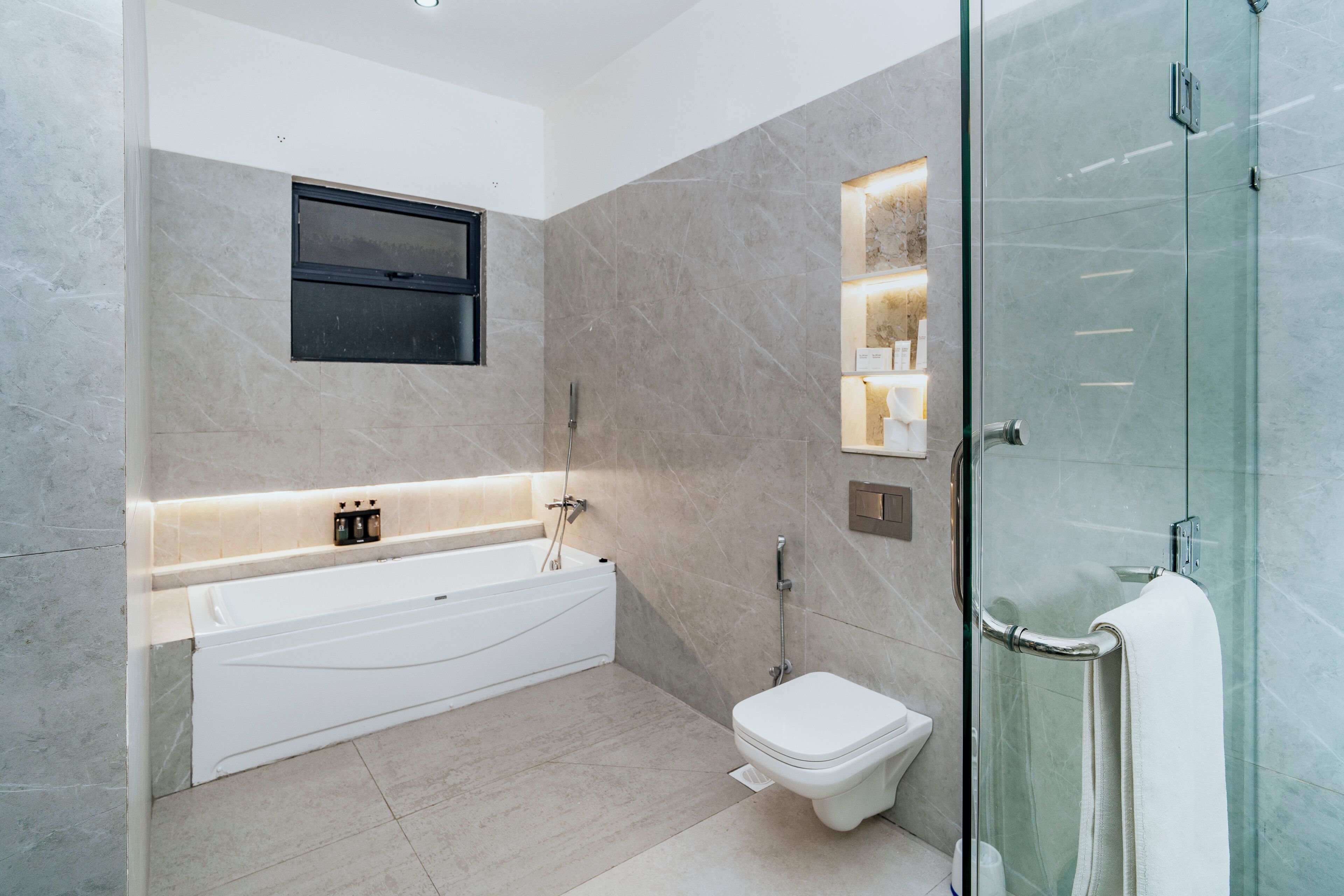 A modern bathroom with a freestanding bathtub, a toilet, and a glass-enclosed shower area.