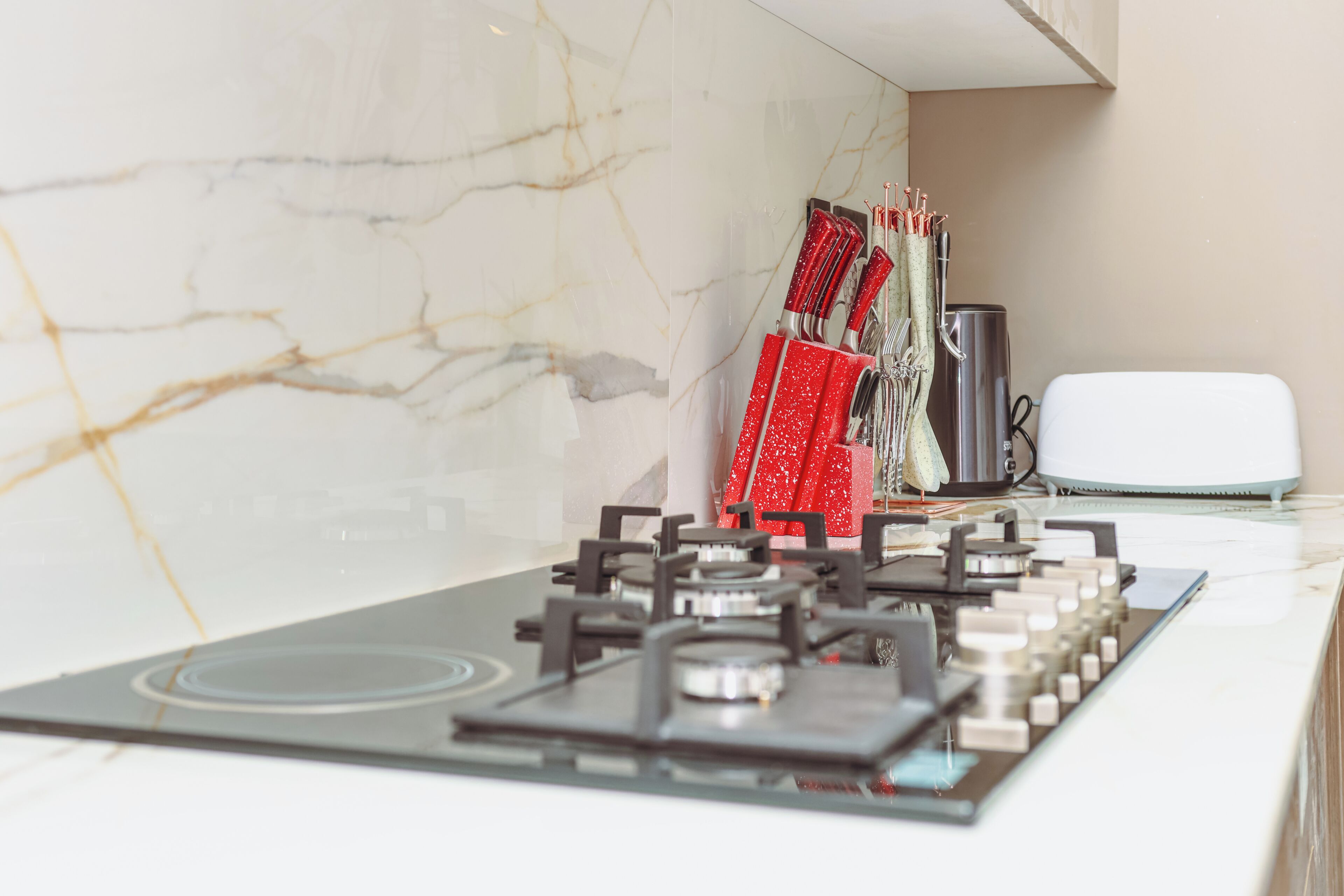 A kitchen with a gas stove, a coffee maker, and a toaster.