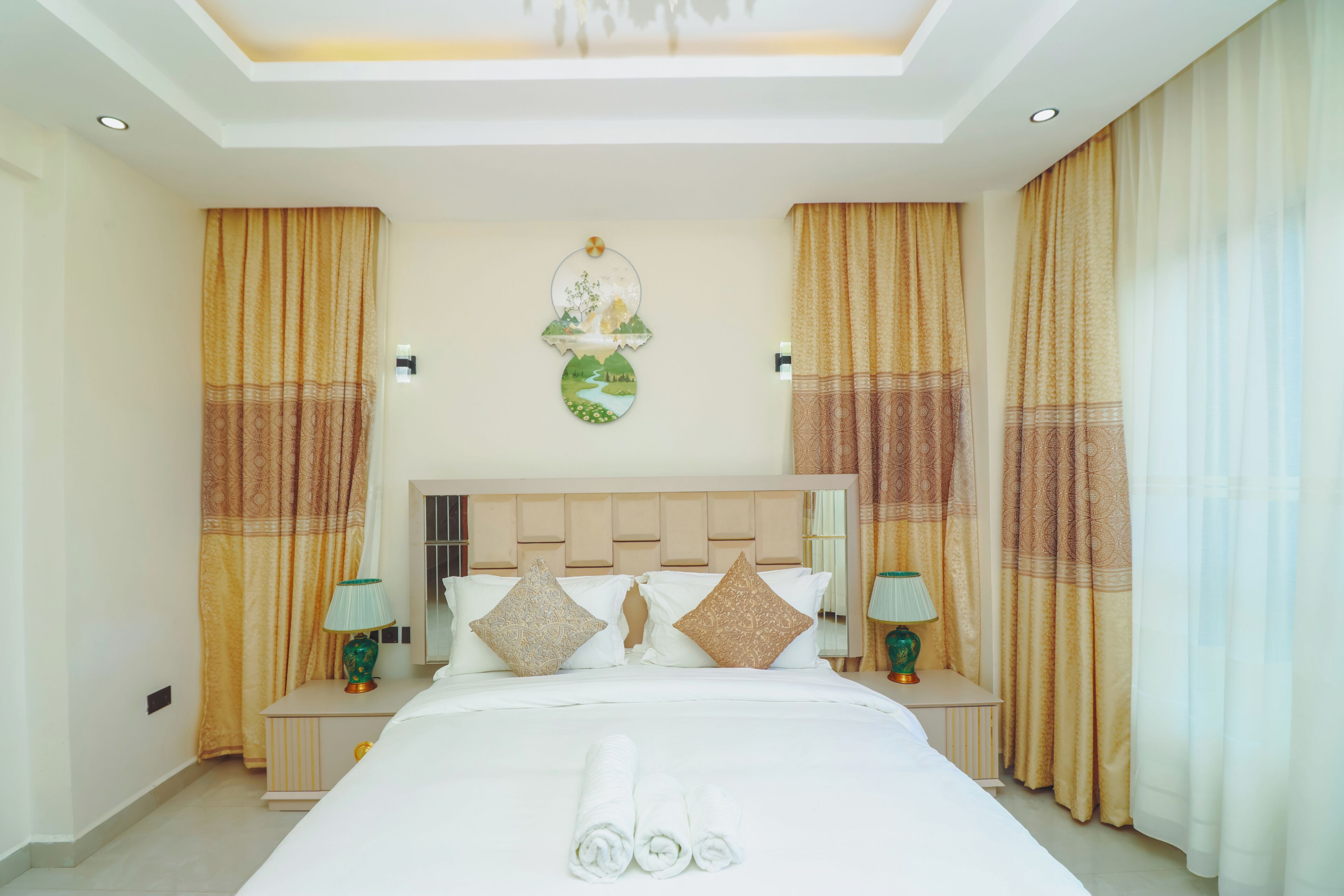 Una camera d'albergo con un letto grande, due comodini, un pannello decorativo e tende.