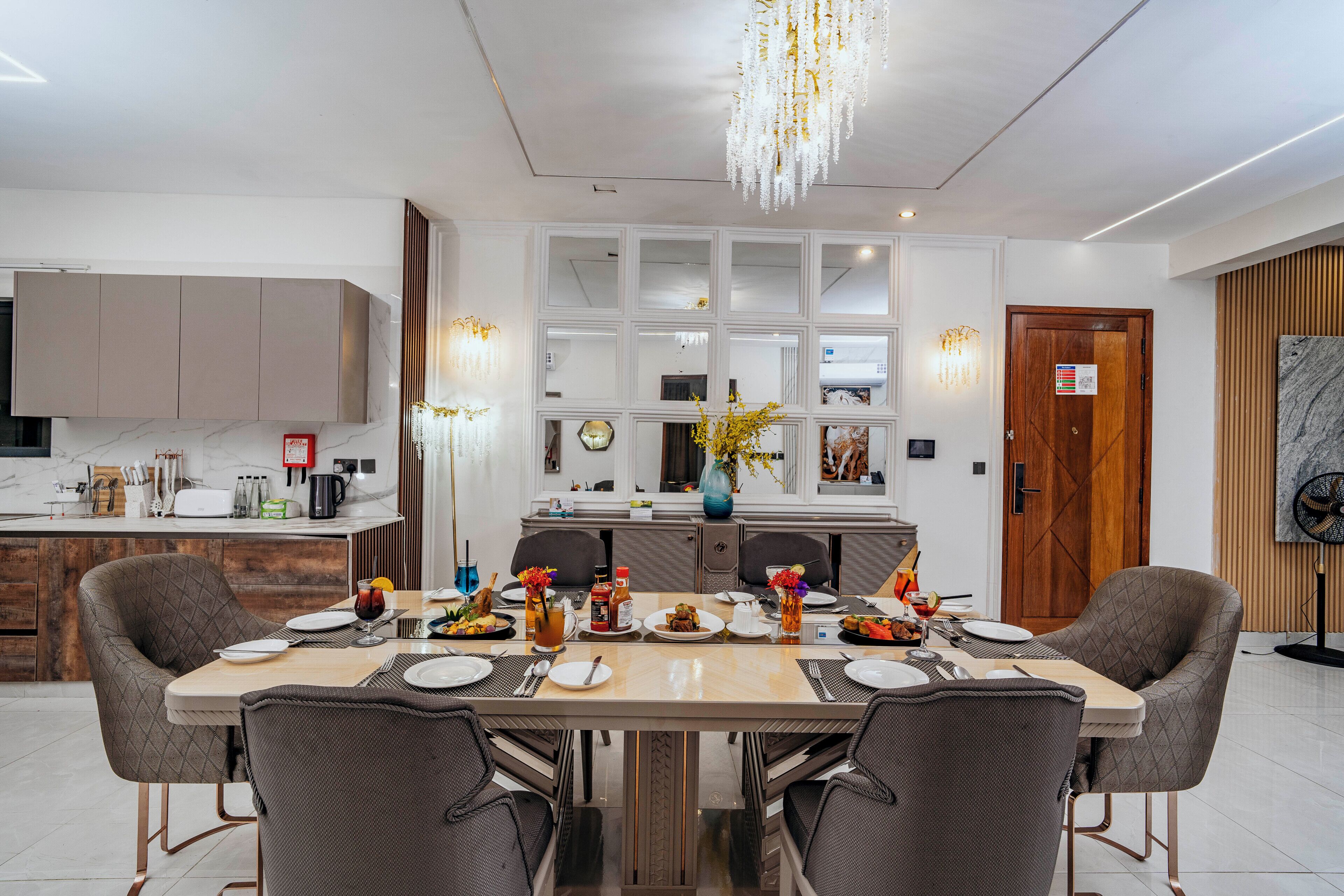 A modern dining area with a large table, chairs, and a chandelier.