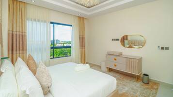 A hotel room with a large bed, a dresser, a mirror, and a view of a cityscape.