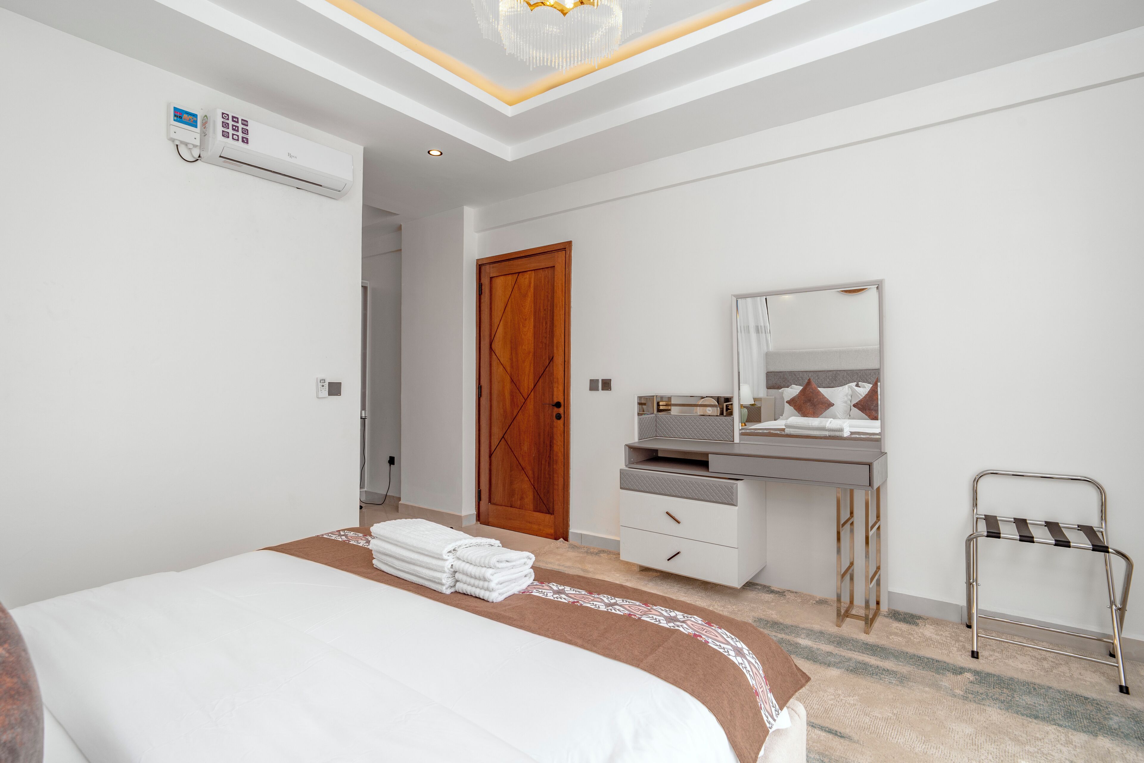 A modern bedroom with a bed, a bedside table, a mirror, a desk, and a chair.