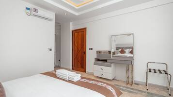 A modern bedroom with a bed, a bedside table, a mirror, a desk, and a chair.