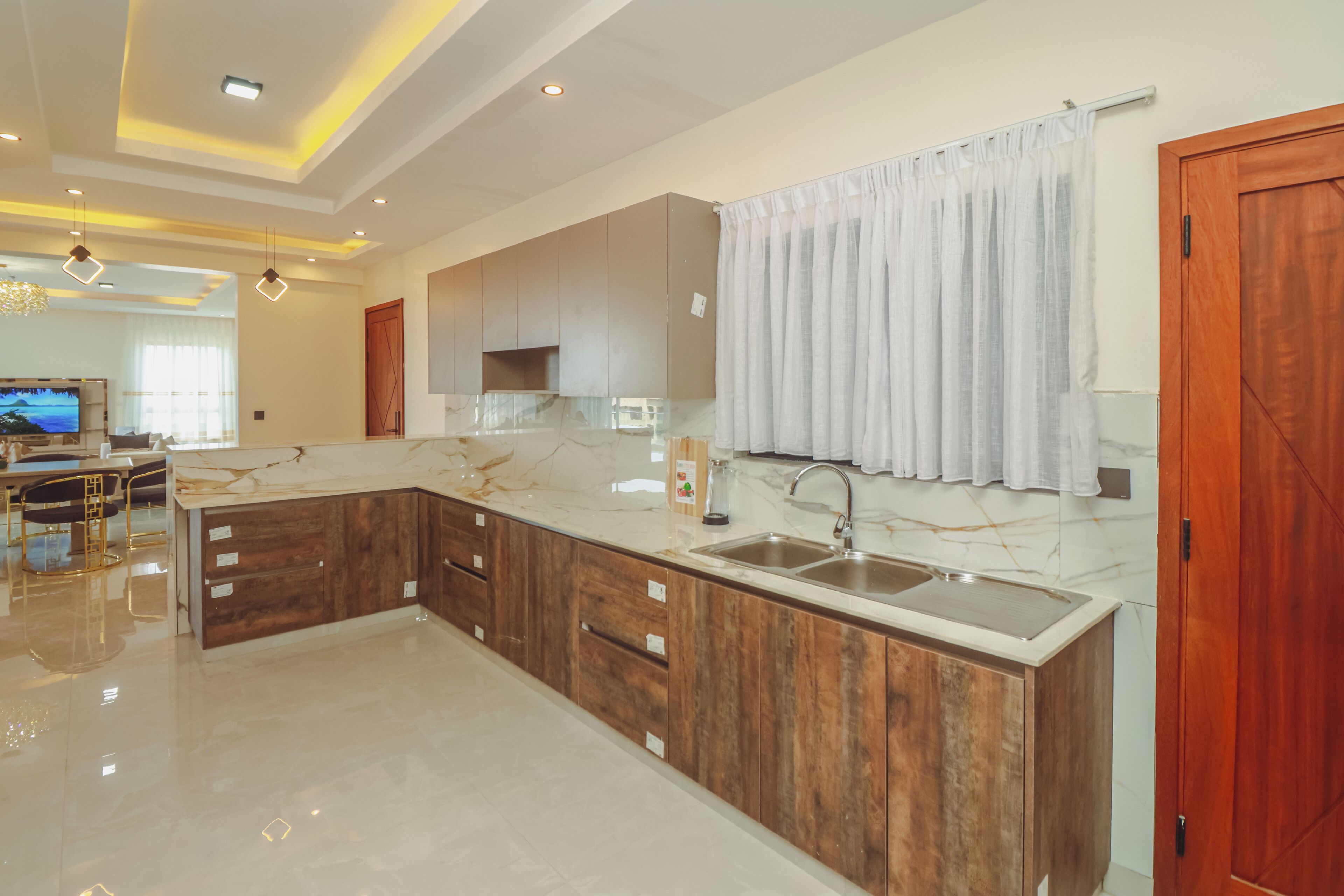 A modern kitchen with marble countertops, wooden cabinets, and a built-in sink.