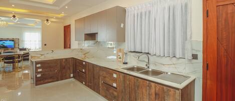 A modern kitchen with marble countertops, wooden cabinets, and a built-in sink.