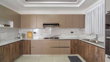 Een moderne keuken met een centraal eiland, inbouwmeubels en een plafond met inbouwspots.